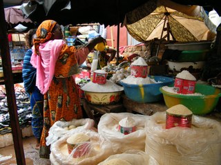 Lady measuring out grains on traditional market stall in Burkina Faso