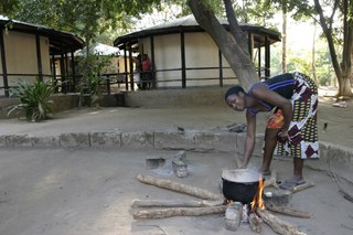 A girl cooking, outside a hut