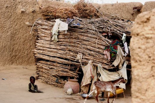 A child sits by the side of a building, Mali