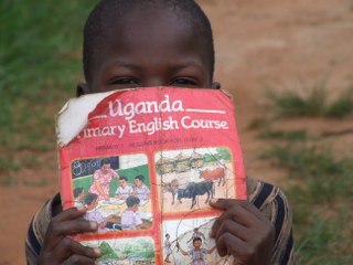 A young child hiding behind his textbook